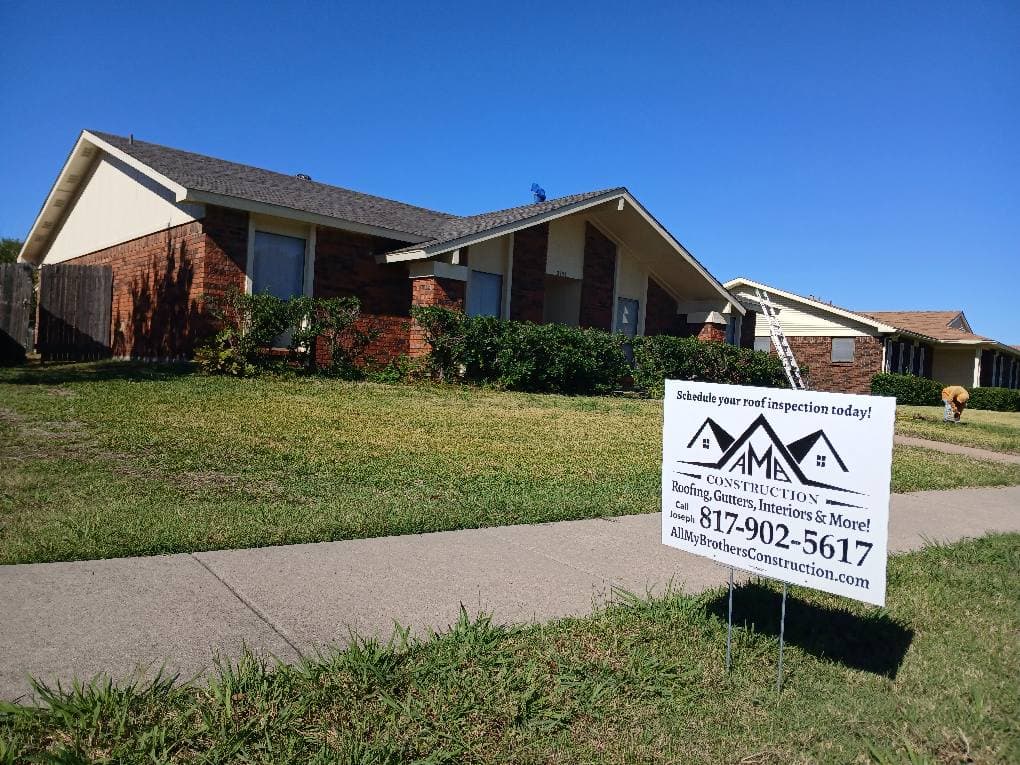 House with sign advertising roof inspection services and construction.