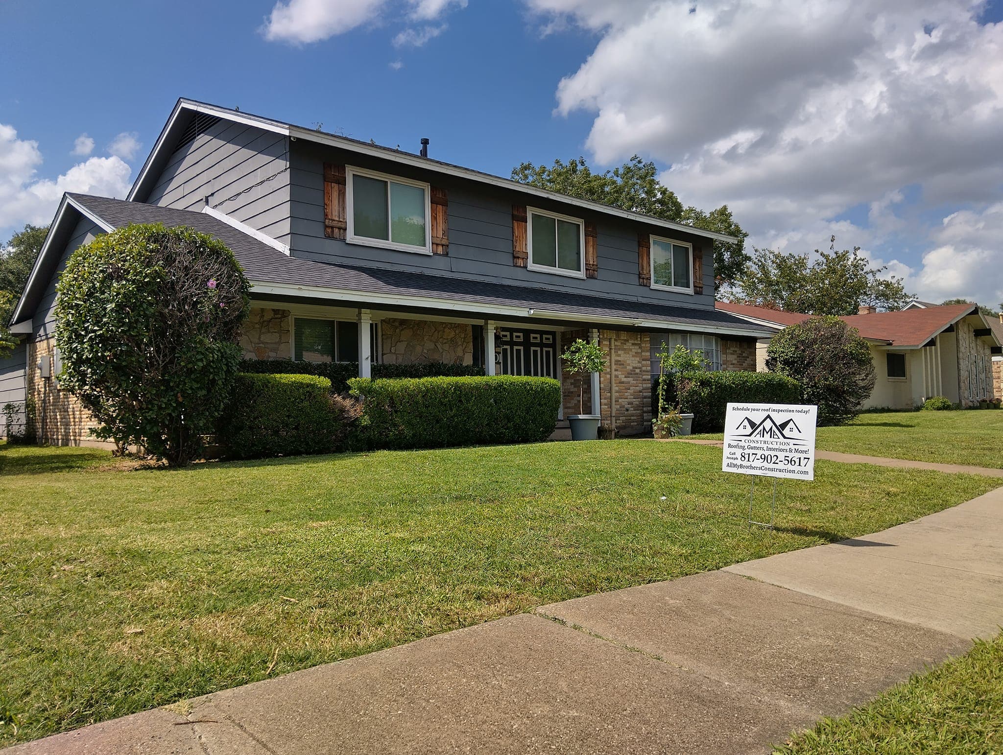 Two-story house with a well-maintained lawn and a for-sale sign in front.